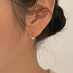 Close-up of gold circle stud earrings with round zircon stones on a female model