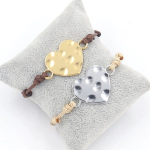 Close-up of gold and silver hammered heart charms on adjustable braided cord bracelets