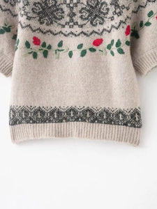 Detail of vintage beige knit sweater with floral embroidery and Fair Isle geometric patterns