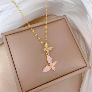 Detailed view of dual butterfly pendants with pink enamel and crystals on a gold chain