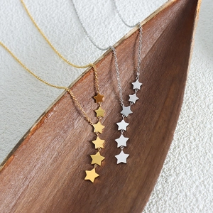 Chic star tassel necklace in gold and silver finish on a rustic leaf background