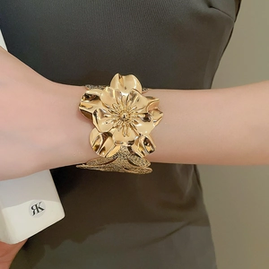 Detail of 3D layered gold flower cuff bracelet with textured metal finish on a model