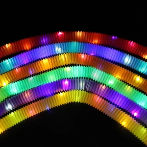 Macro shot of glowing LED rainbow pop tubes arranged in an arch on a dark background