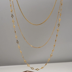 Detailed close-up of 18K gold plated triple layered necklace with heart and snake chains