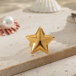 Polierter goldener Pentagramm Sternenring auf naturfarbenem Stein mit Muscheln