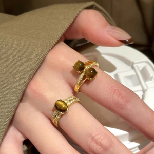 Dettaglio dell'anello con occhio di tigre placcato in oro e zirconi sulla mano della modella
