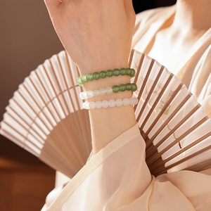 Elegant jade-style beaded bracelets set worn with a traditional Chinese fan background
