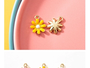 Macro shot of 3D alloy daisy charms with yellow and pink enamel on colorful plates