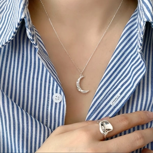 Silver 925 crescent moon necklace and irregular ring worn by a model in a casual setting