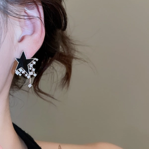 Close-up of elegant black star drop earring with silver frame and zircon on model's ear