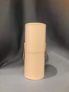 Detail of beige leather makeup brush holder cylinder with secure snap closure buttons