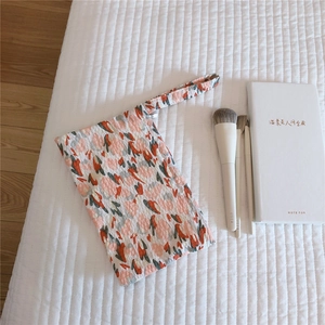 Detail view of floral cotton mini wristlet bag with quilted texture and makeup brushes