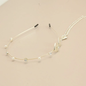 Detail of gold metal headband with white pearls, rhinestones, and long fringe tassels