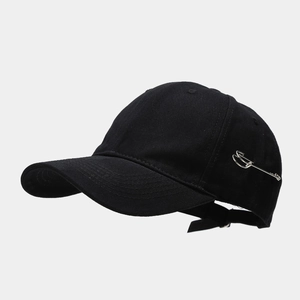 Detail of black cotton baseball cap with silver safety pin accent in streetwear style