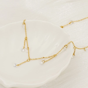 Minimalist gold stainless steel necklace with sparkling round zircon tassel pendants on a shell