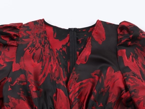 Détail du col en V et de la texture du tissu jacquard rouge et noir sur la robe