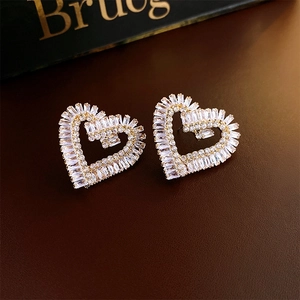 Macro shot of gold-plated hollow heart studs with cubic zirconia on leather