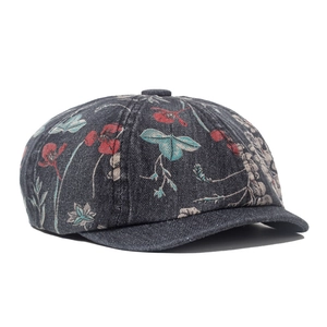 Detailed close-up of dark grey denim newsboy cap featuring red poppy floral embroidery