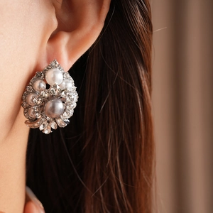 Close-up of vintage baroque pearl earrings with rhinestones on a female model
