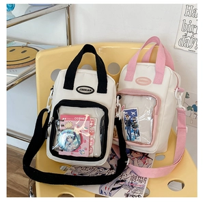 Detail of canvas itabag with clear window displaying pins, in black and pink strap options