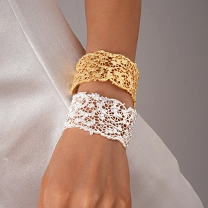 Detail of gold and silver open bangles with intricate cutout lace texture on silk fabric