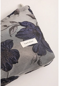 Close-up of vintage dark blue floral jacquard fabric and high-quality zipper on makeup bag
