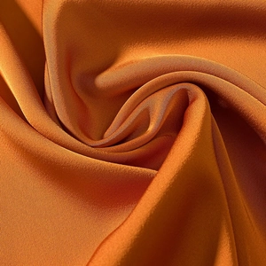 Elegante abito lungo in raso arancione con tessuto lucido e dettagli in metallo decorativo