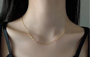 Dettaglio della collana a catena dorata indossata su una modella per un look di tendenza