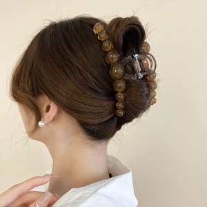 Close-up of a large amber resin hair claw clip holding hair in a refined bun style