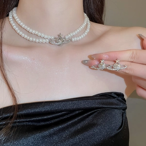 Close-up of double-layer pearl necklace and star-orb earrings worn on a model