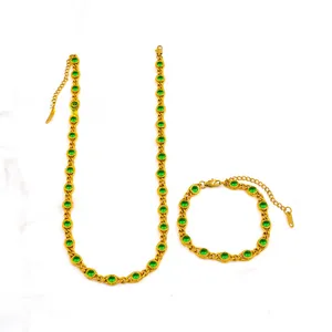 Detail view of gold jewelry set with necklace, bracelet, and green zircons
