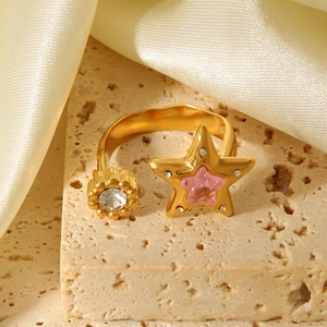 Detailed close-up of a gold star ring with pink zircon on beige stone and champagne silk