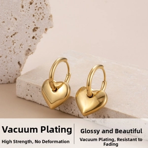 Detailed view of glossy gold heart pendant earrings on a stone display stand