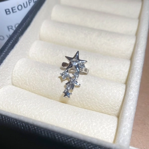 Vue macro d'un earcuff étoile en argent avec zircons brillants sur écrin velours