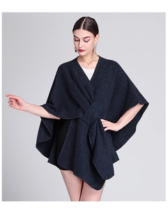 Detail of a dark blue oversized knit poncho with an irregular hem and soft fabric texture