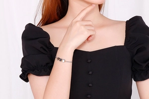 Detail of adjustable silver and black metal bracelet with tulip charms on model's wrist