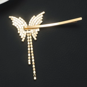 Detailed view of a golden butterfly hair clip with sparkling rhinestones and long tassels