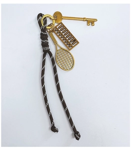 Detail of hand-woven rope keychain with vintage gold key, abacus, and tennis racket charms