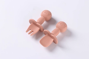Detail of pink silicone baby spoon and fork set with bear head wooden handle and guard