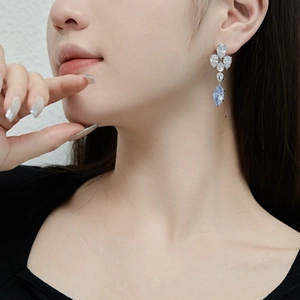 Détail de boucles d'oreilles pendantes en argent S925 et zircon bleu sur modèle femme