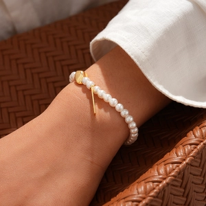 Detail of 18k gold plated pearl chain bracelet with OT toggle clasp on female wrist