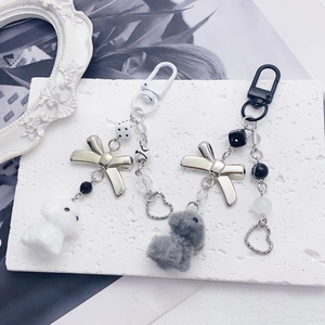 Chic plush bunny keychain with metal bow and beaded chain on a decorative stone surface