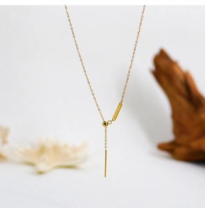 Close-up of golden minimalist vertical bar pendants on a fine adjustable chain