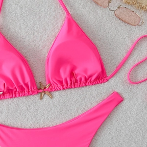 Neon pink two-piece bikini featuring a golden starfish buckle on a white texture