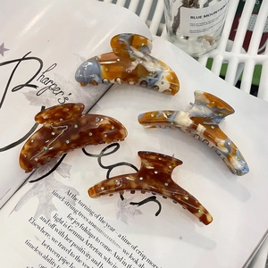 Close-up of acetic acid hair claws with colorful rhinestones on fashion magazine background