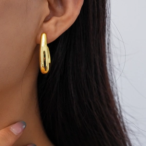 Close-up of polished gold-tone curved earring worn by a model for a minimalist look