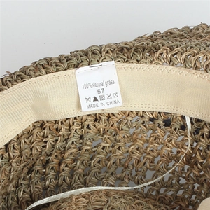 Detail view of the 100% natural grass straw hat label and breathable woven texture