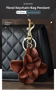 Detail of dark brown leather camellia flower keychain on a black quilted handbag