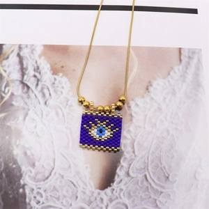 Macro detail of Bohemian evil eye beaded pendant necklace with golden metal accents