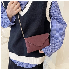 Close-up of wine red matte envelope bag with golden chain strap on model's shoulder